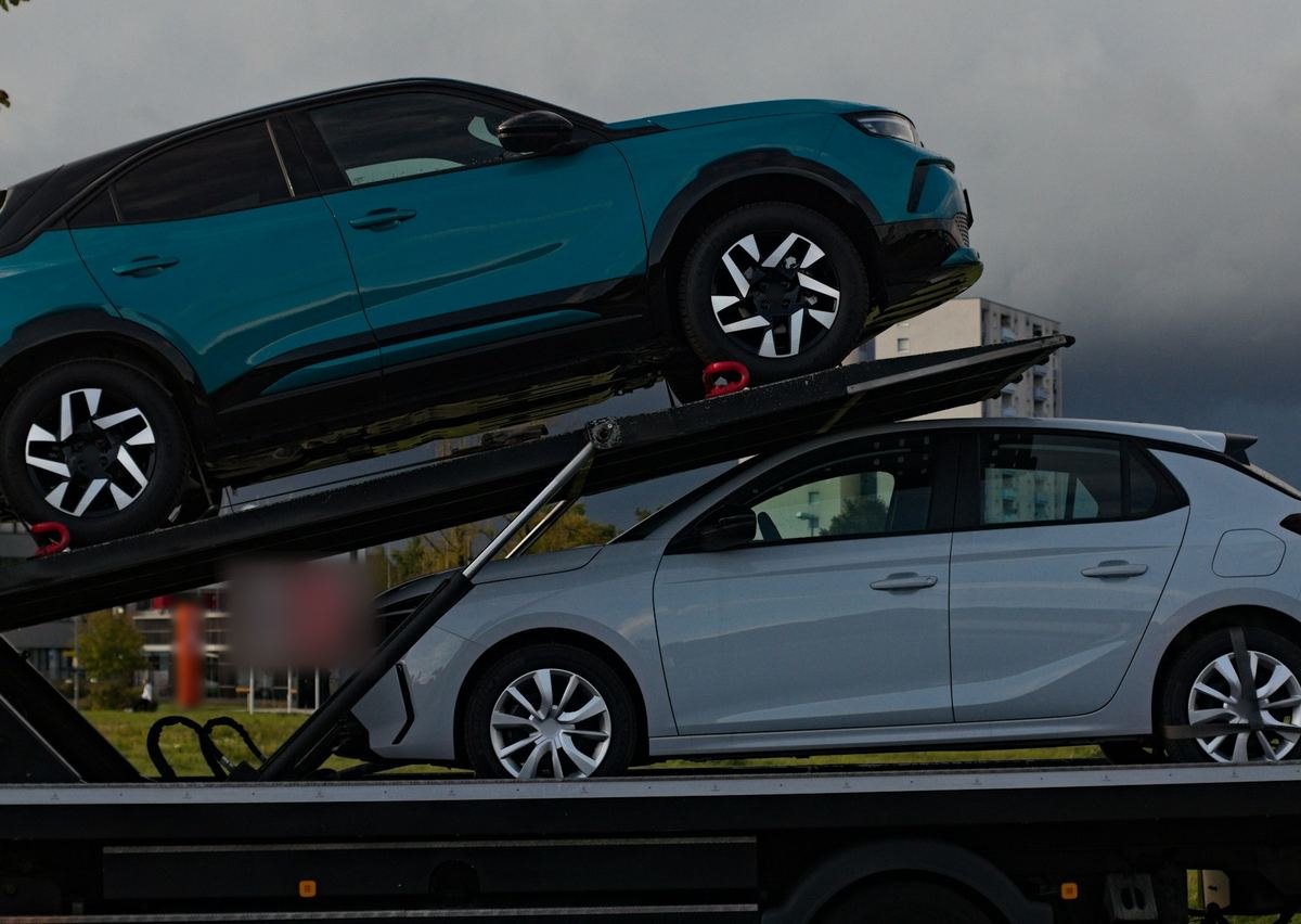 Twee wagens vastgezet op een autotransporter, onder een donkere lucht